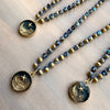 Three beaded necklaces with celestial pendants on a wooden surface