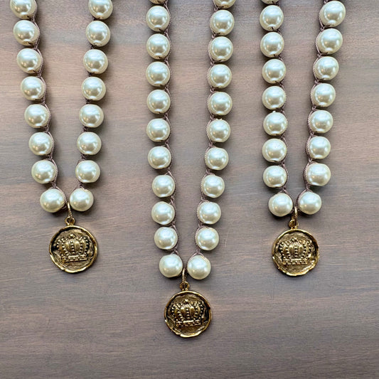 Three pearl necklaces with gold pendants on a wooden surface
