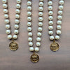 Three pearl necklaces with gold pendants on a wooden surface