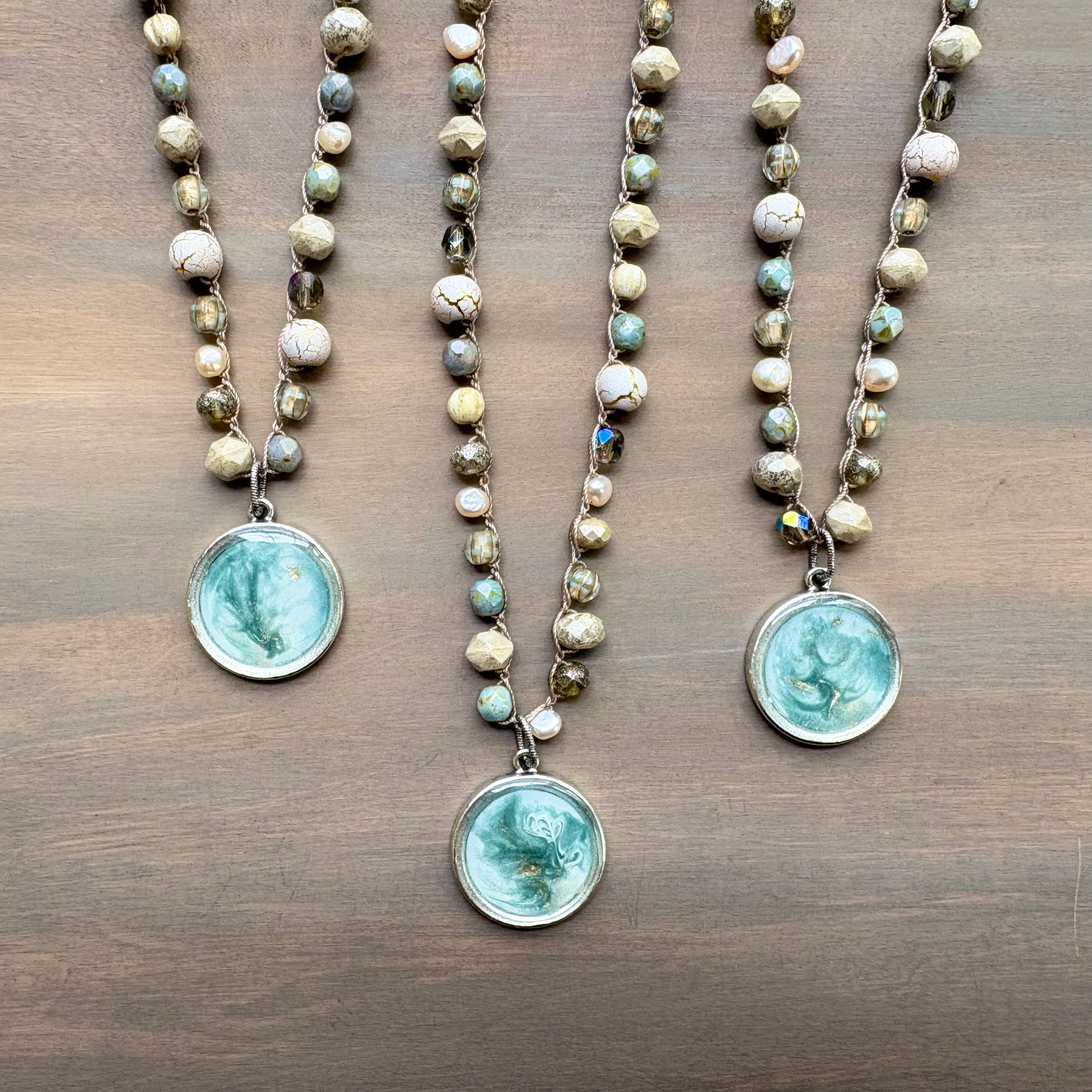 Three beaded necklaces with turquoise pendant on a wooden surface
