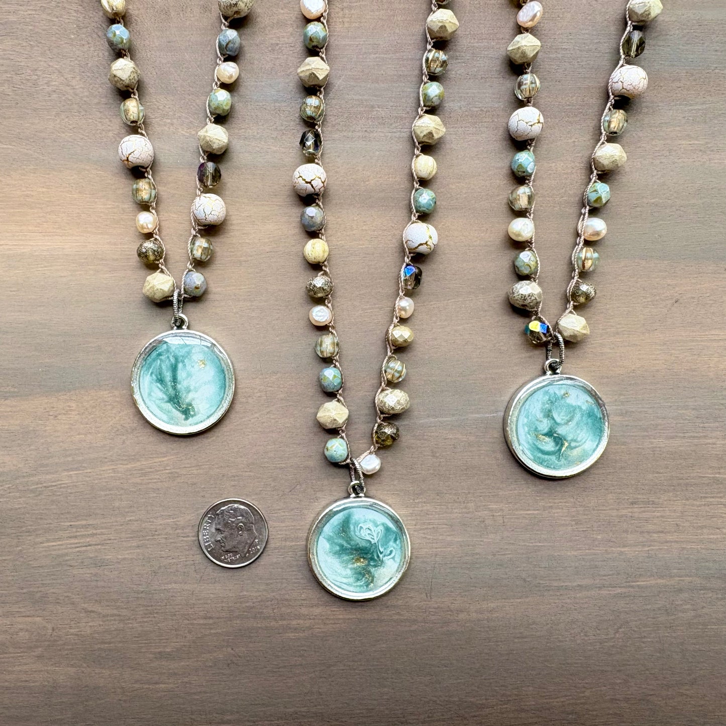 Three beaded necklaces with pendant stones on a wooden surface