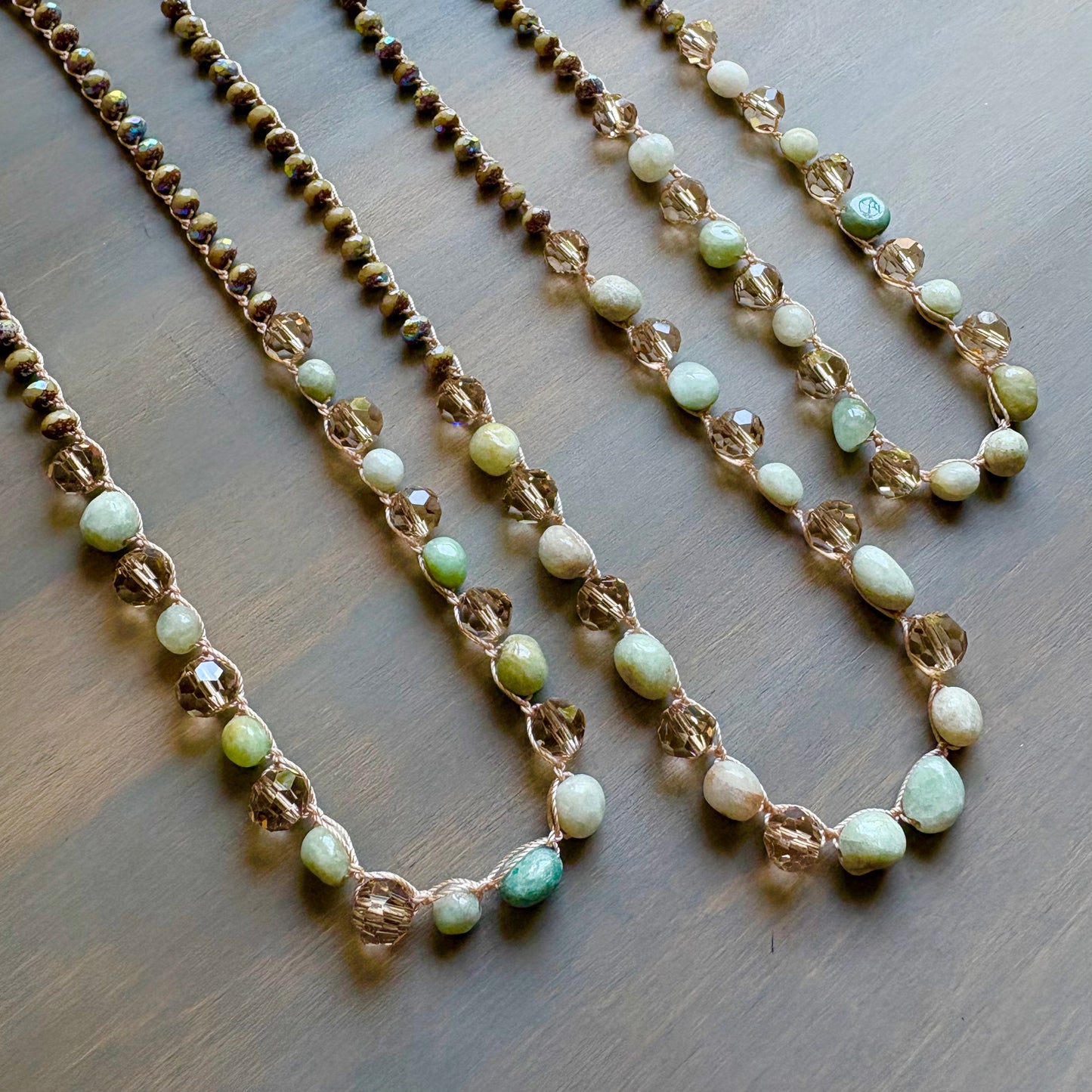 Two beaded necklaces with green and white beads on a wooden surface