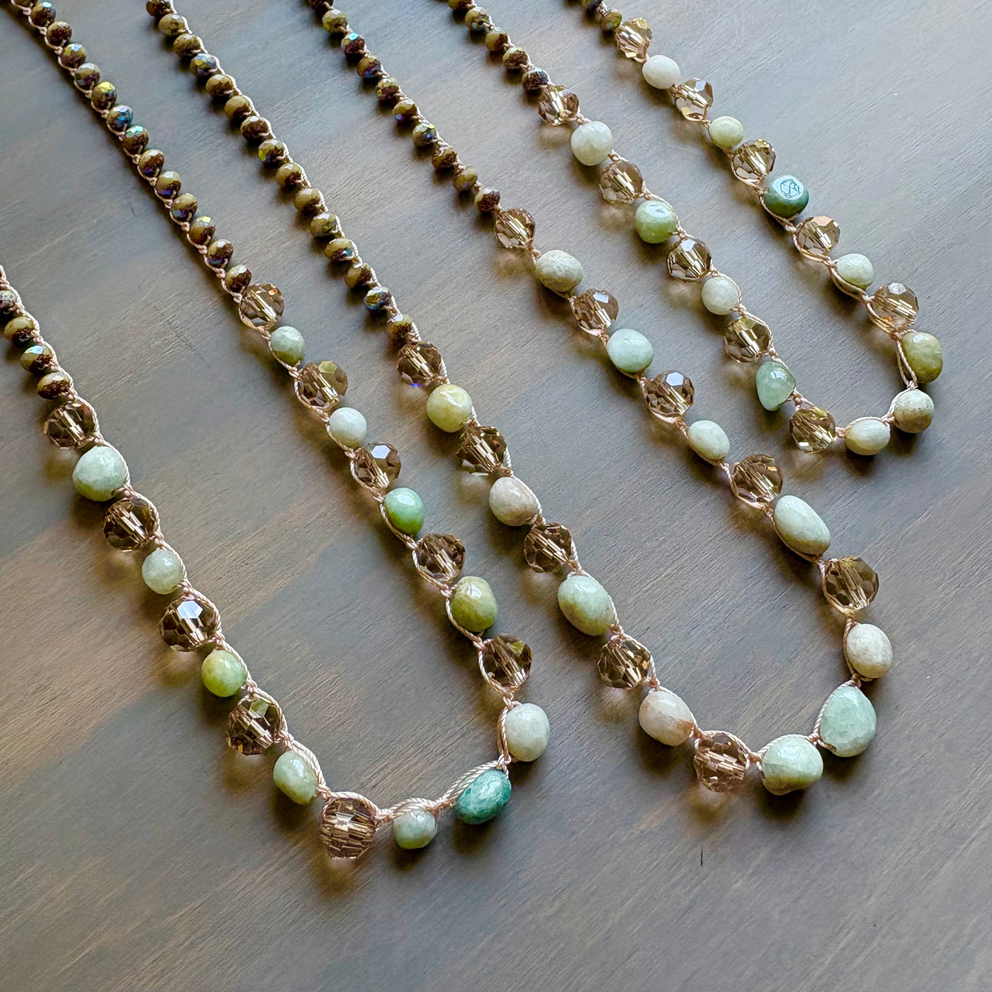 Two beaded necklaces with green and white beads on a wooden surface