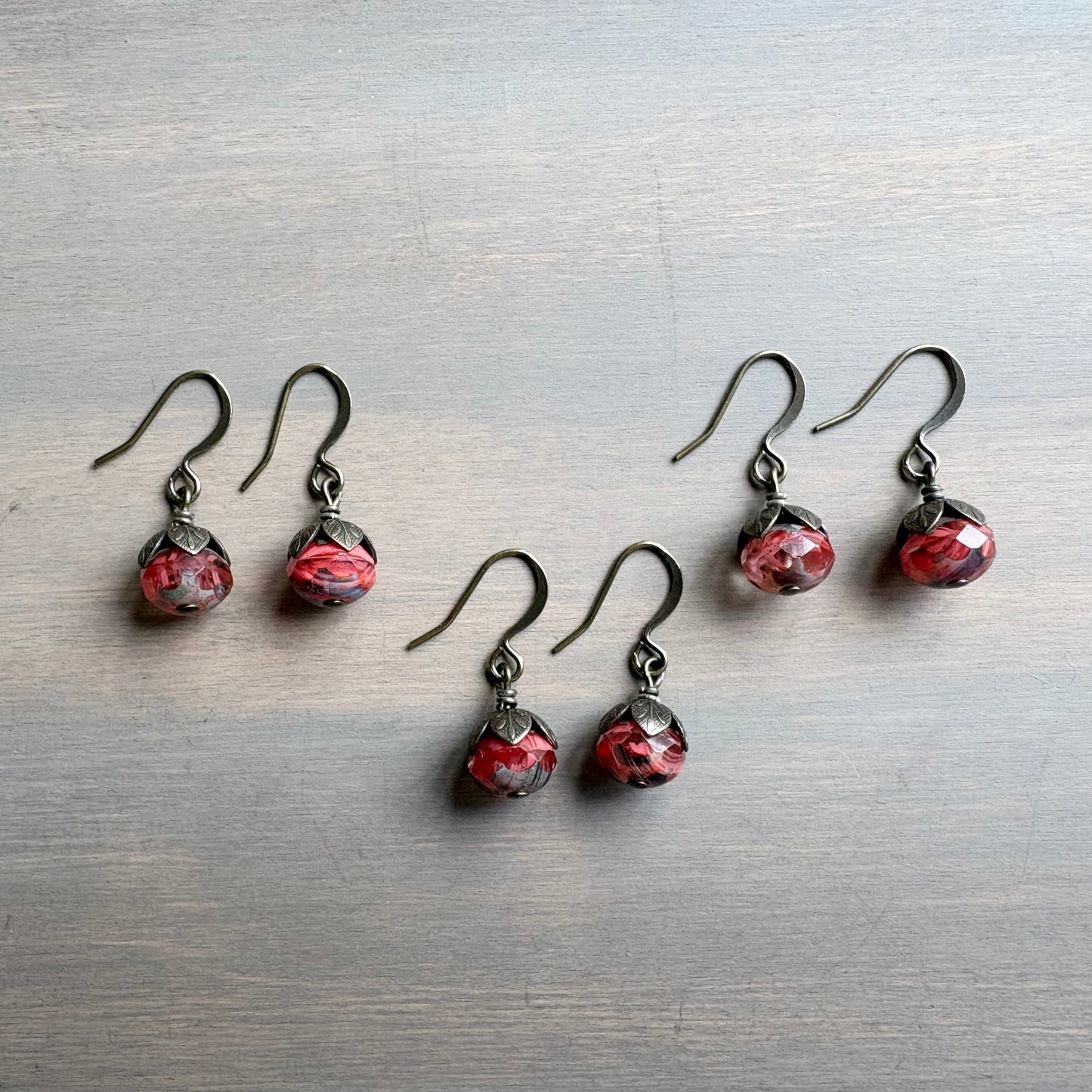 Set of red and black teardrop earrings on a metallic surface