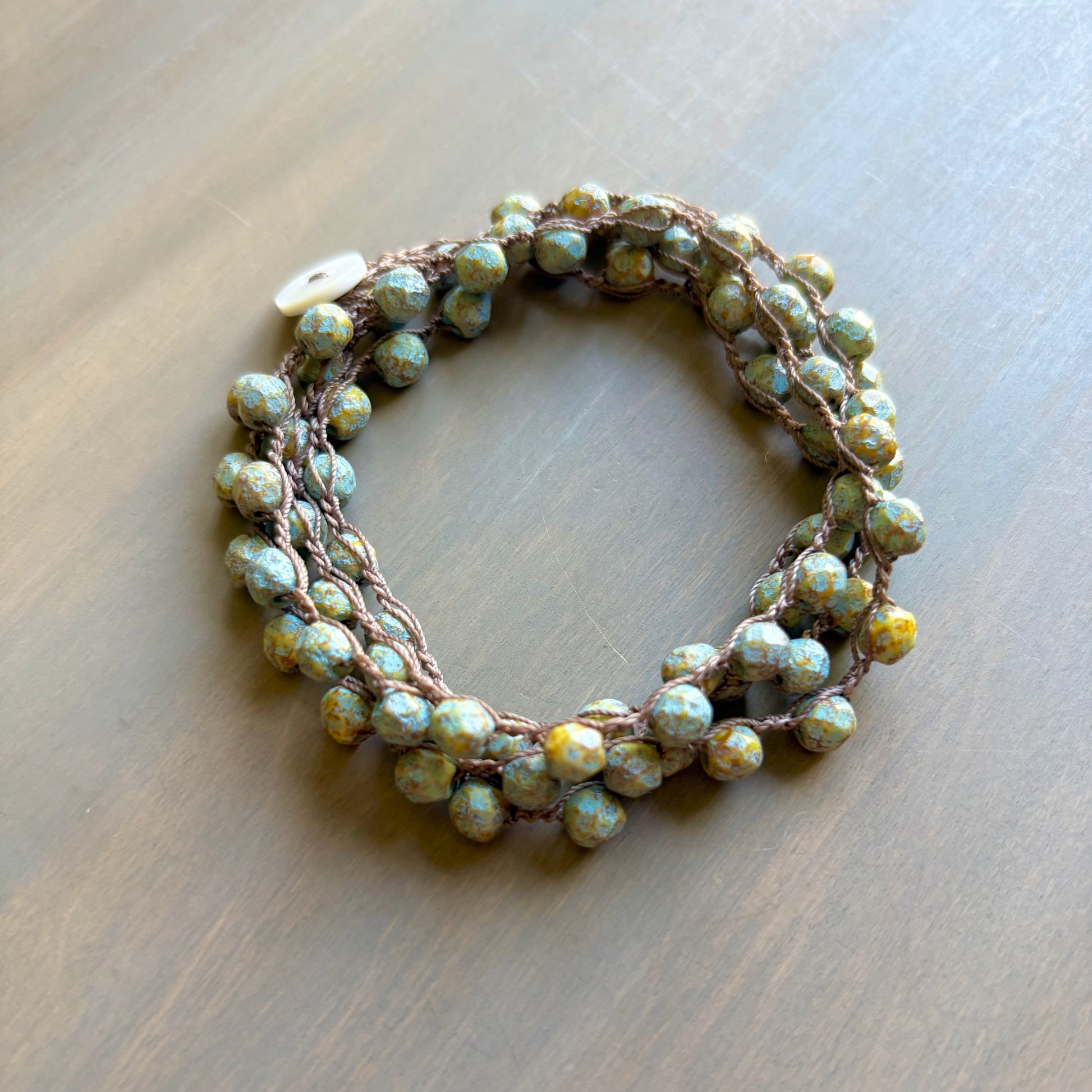 Bracelet with green and brown beads on a wooden surface
