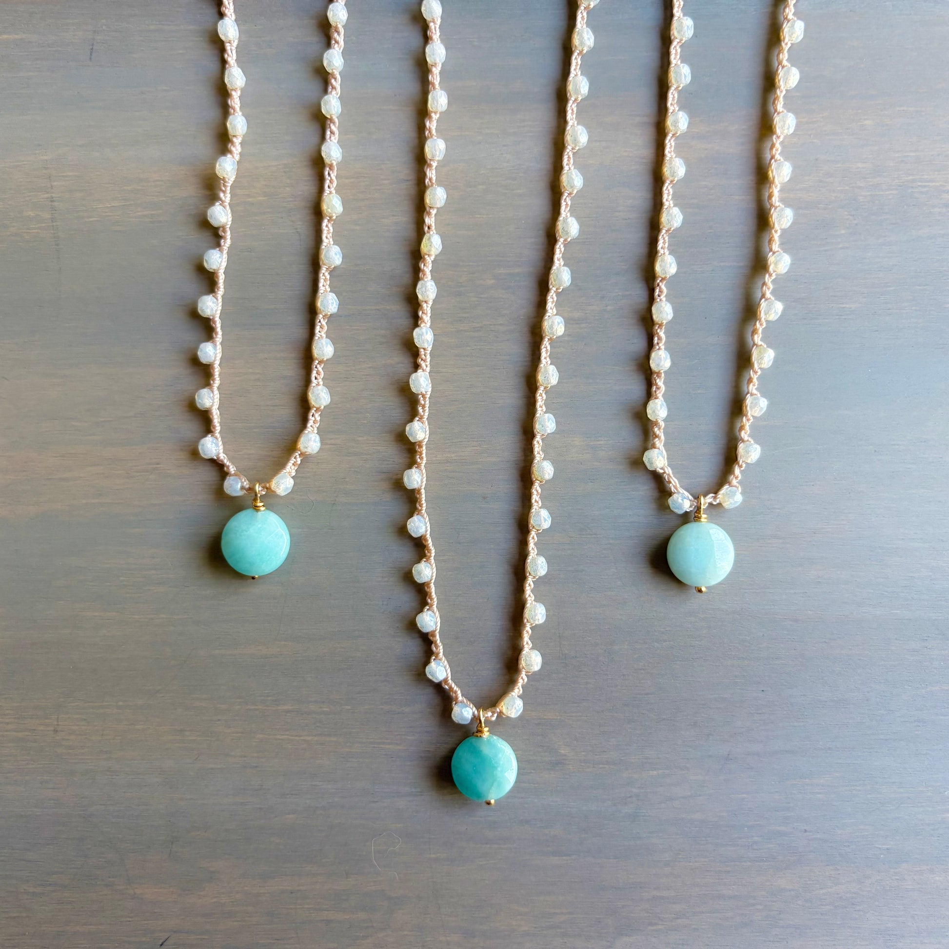 Three pearl necklaces with turquoise beads on a wooden surface