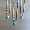 Three pearl necklaces with turquoise beads on a wooden surface