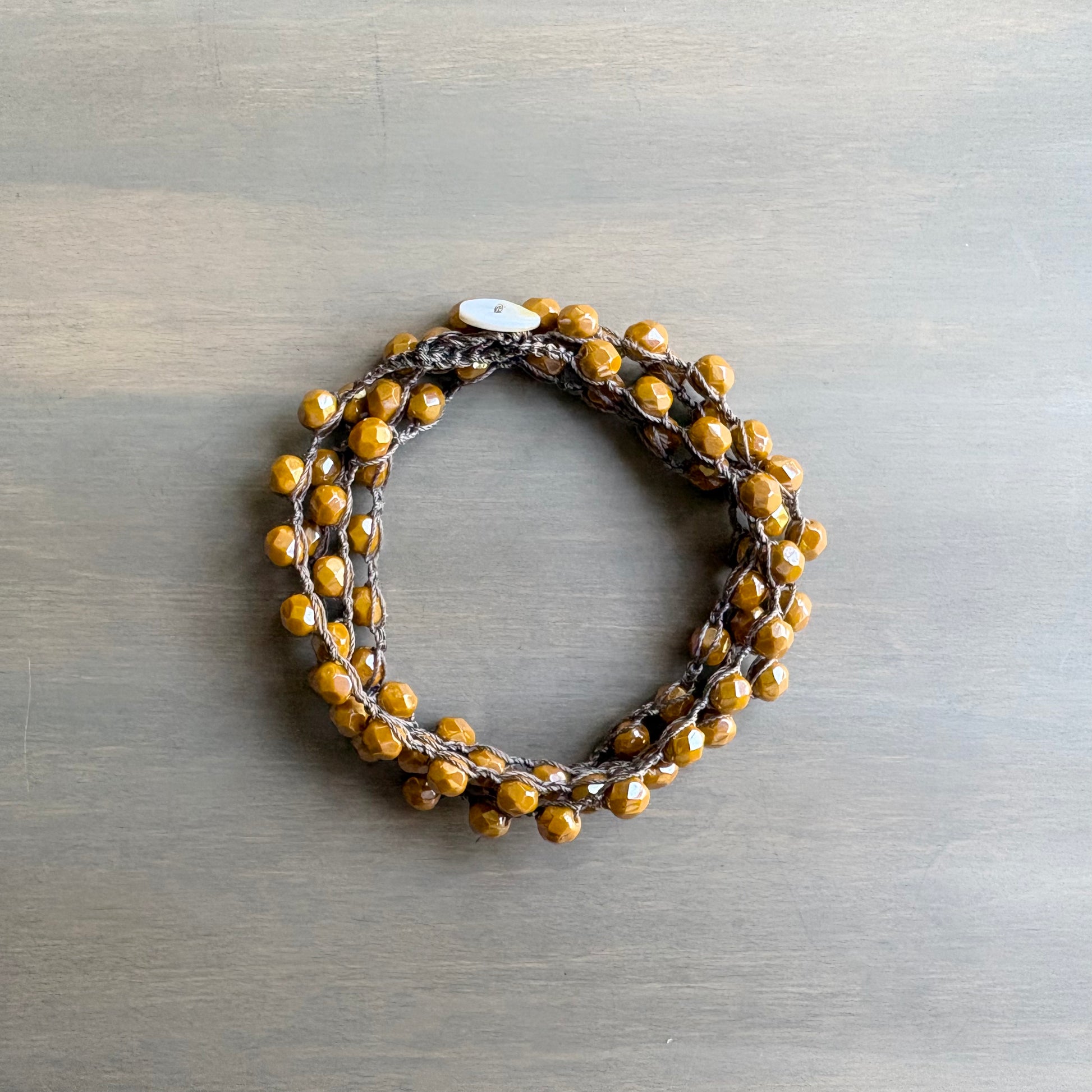 Bracelet with brown and yellow beads on a metallic surface