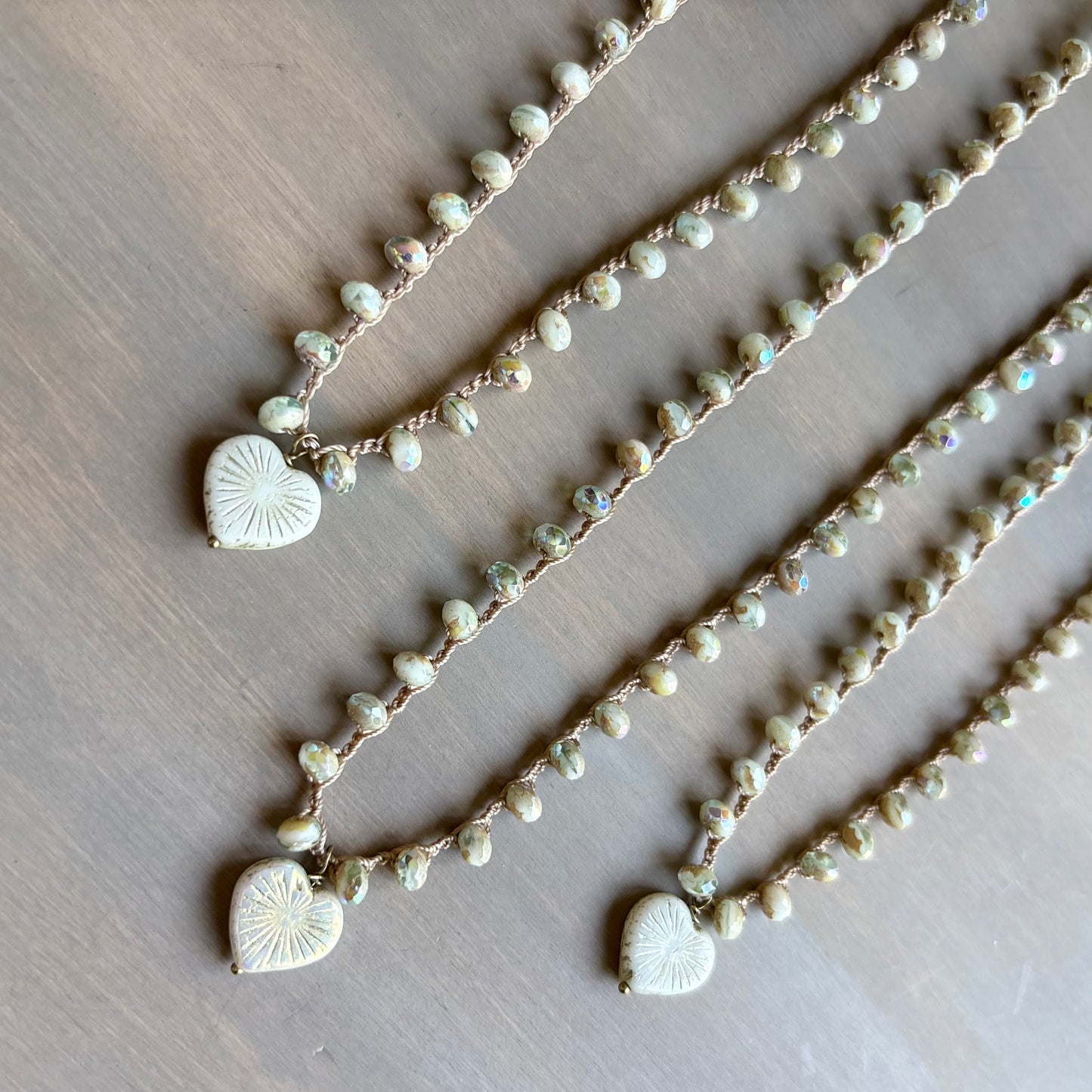 Two pearl necklaces with heart-shaped charms on a wooden surface