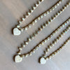 Two pearl necklaces with heart-shaped charms on a wooden surface